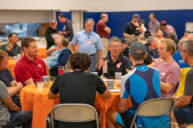 Group of adult men sitting around a table eating breakfast